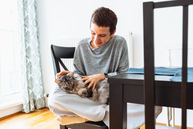 Attractive young girl holding purring cat in arms