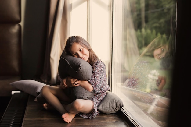 Attractive young girl near the window in a blue dress