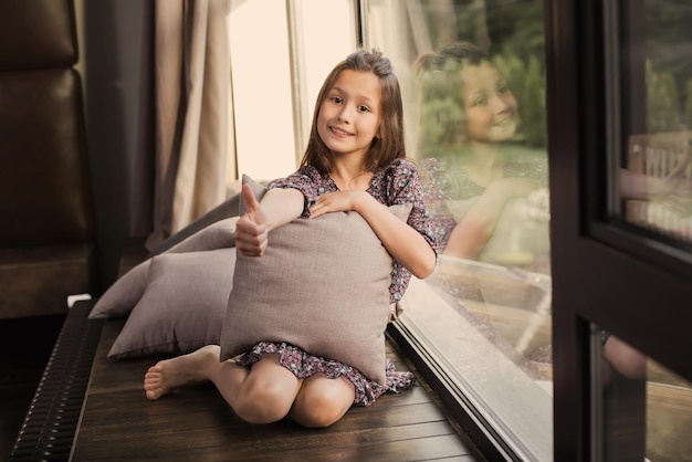 Attractive young girl near the window in a blue dress