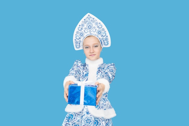 Attractive young girl wearing blue suit of snow maiden holding gift box. Isolated on blu background