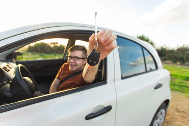 Attractive young happy man showing his new car keys and laughing.