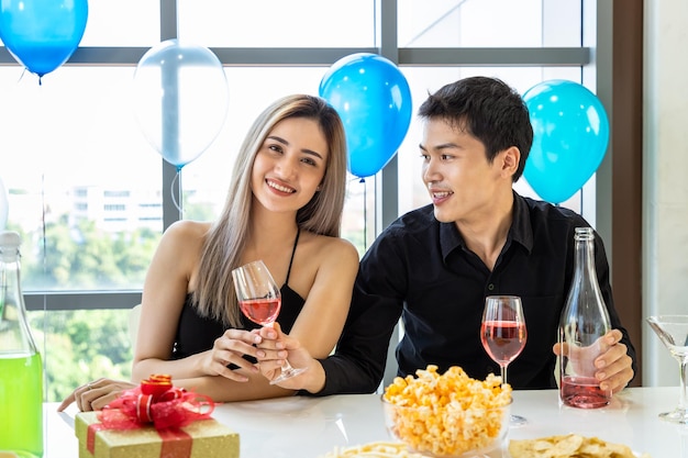 Attractive young male and female celebrate Christmas and New Year in office party man give glass of wine to woman