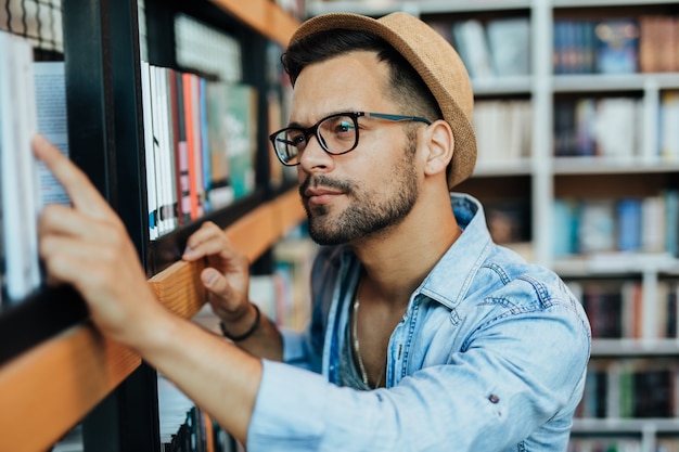 Attractive young male student choosing books in the bookstore