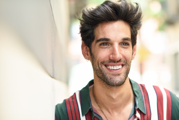 Attractive young man with dark hair and modern hairstyle wearing casual clothes outdoors