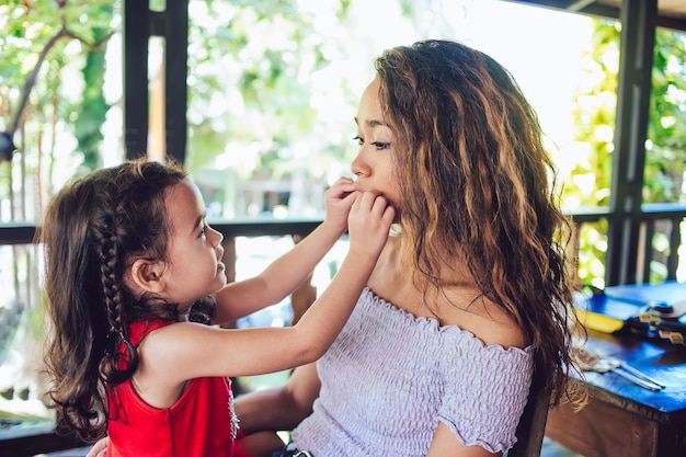 Attractive young mother and adorable little daughter having fun at restaurant