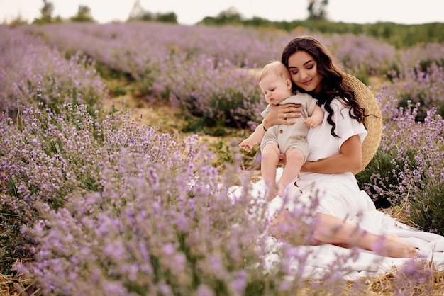 Attractive young mother playing with her baby in a lavender field