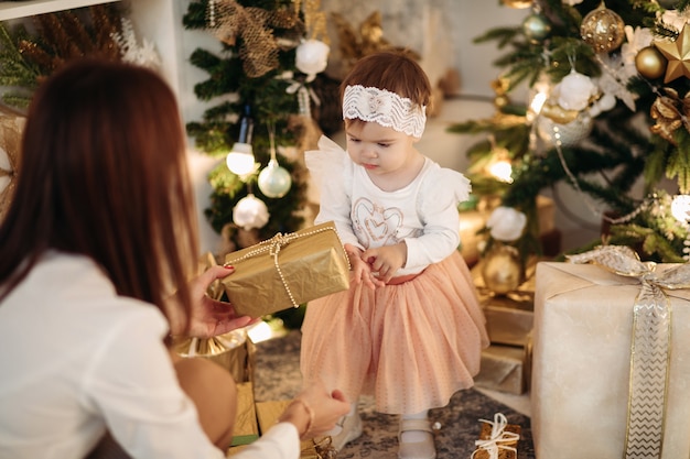 Attractive young mother with dark hair gives a present to her little daughter