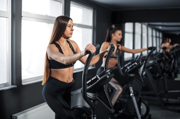 Attractive young sports woman is working out in gym. Doing cardio training on treadmill. Running on treadmill. High quality photo