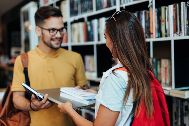 Attractive young students man and woman choosing books in the bookstore.