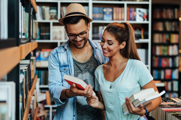 Attractive young students man and woman choosing books in the bookstore.