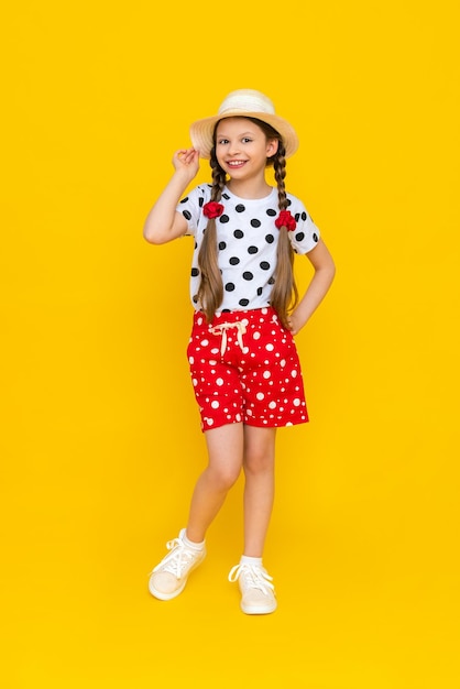 An attractive young teenage girl in a straw hat and summer clothes a girl in a white Tshirt and red shorts on an isolated background a space for copying The concept of summer holidays