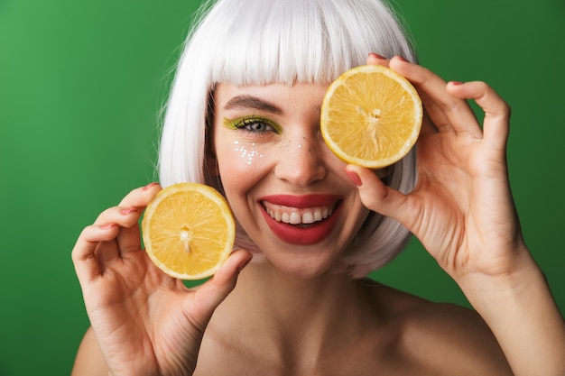 Attractive young topless woman wearing short white hair standing isolated, showing sliced lemon