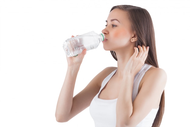 Attractive young woman drinking water. Female holding bottle of water.