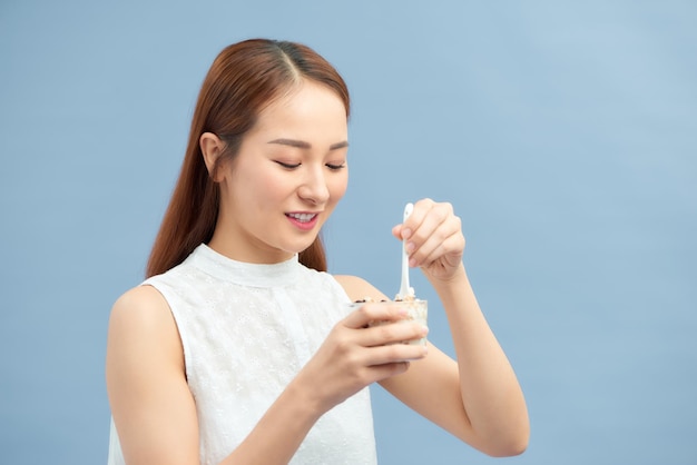 Attractive young woman enjoying a healthy meal eating a mixture of yoghurt and muesli with fruit