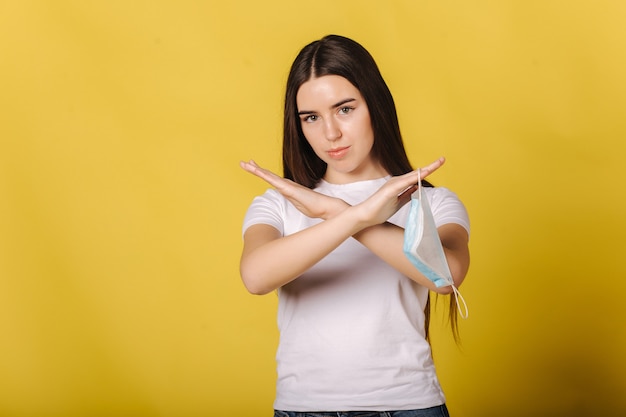 Attractive young woman hold protective mask in hand and think of its necessity female cross arms