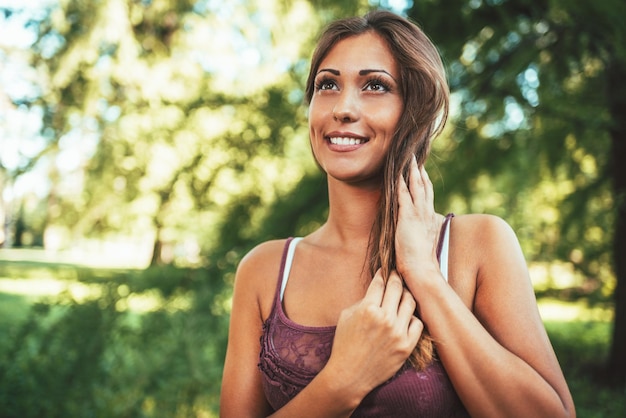 Attractive young woman is enjoying her time outside in park with sunset in background.