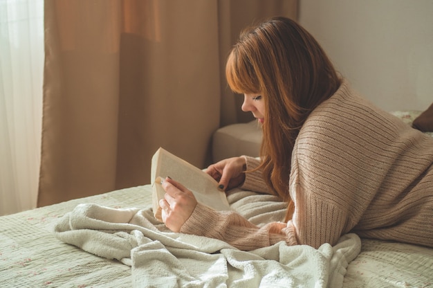 Attractive young woman is reading a book at home