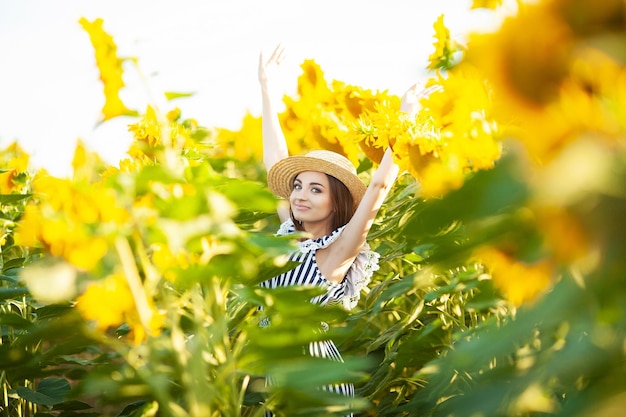 Attractive young woman model posing in field of sunflowers