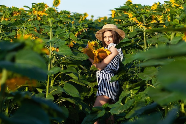 Attractive young woman model posing in field of sunflowers