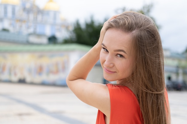 Attractive young woman posing with red dress in the street