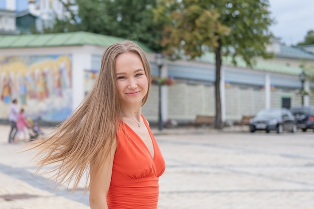 Attractive young woman posing with red dress in the street