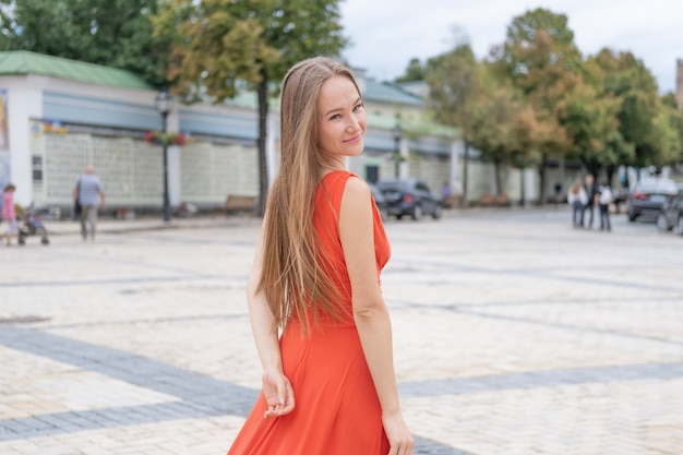 Attractive young woman posing with red dress in the street