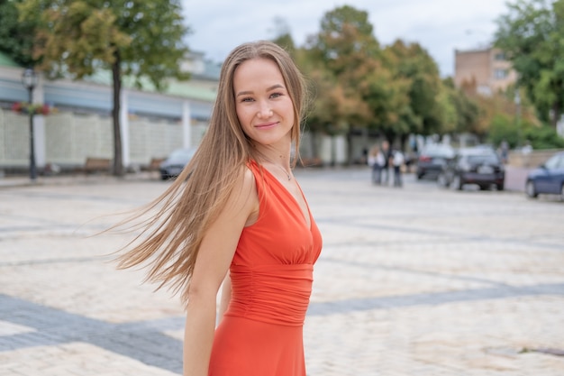 Attractive young woman posing with red dress in the street