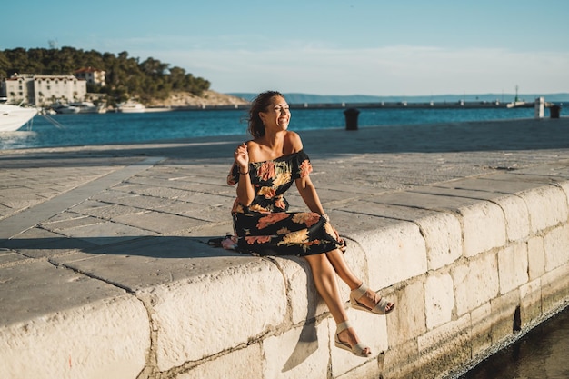 An attractive young woman sitting on the wonderful seaside of Mediterranean and enjoying a summer vacation.