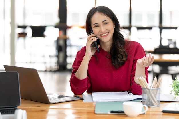 Attractive young woman talking on the mobile phone and smiling while sitting at her working place in office