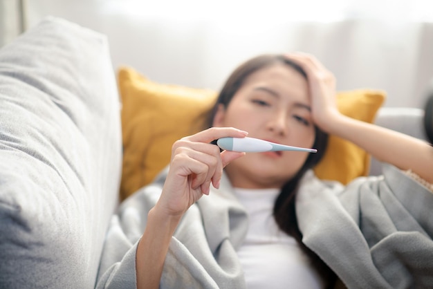 Attractive young woman using a thermometer to measure fever