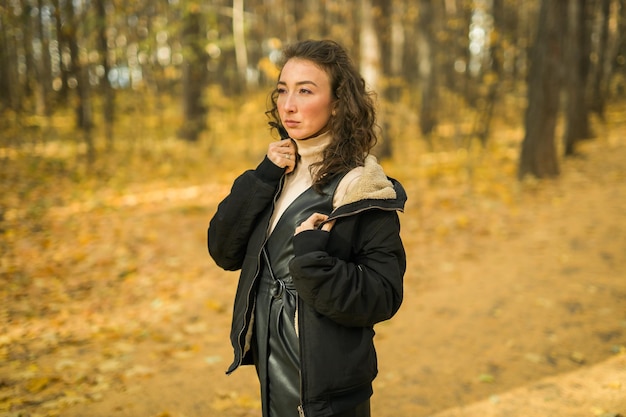 Attractive young woman walking in autumn park happy mood and fashion style trend and curly long