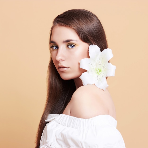 Attractive, young woman on a white background. Portrait of a beautiful girl with a bouquet of white flowers.