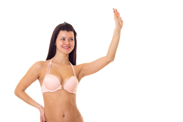 Attractive young woman with long black hair in pink swimming suit on white background in studio