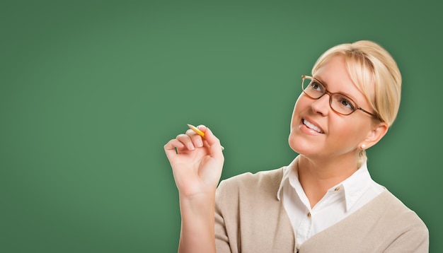 Photo attractive young woman with pencil in front of blank chalk board