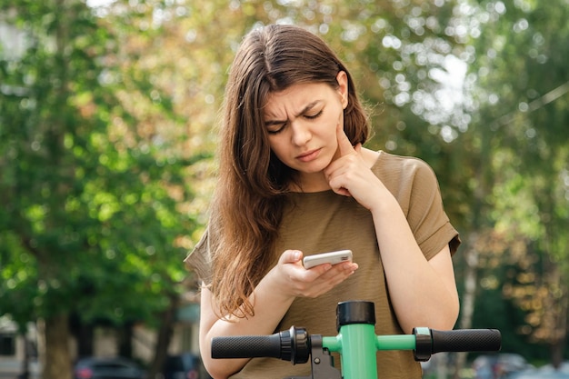 Attractive young woman with a rental electric scooter on a sunny day