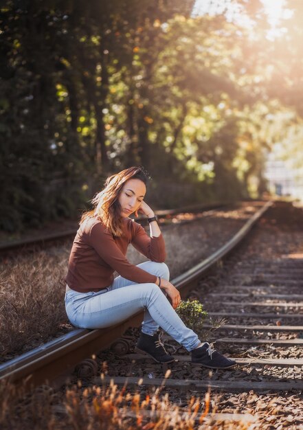 An attractive young woman with a sad pensive expression in a park on a sunny day Shallow depth of field female creative portrait