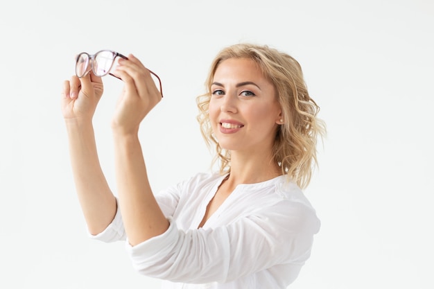 Attractive young woman with spectacles on white wall. Vision glasses. Optics shop.