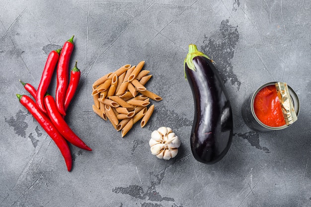 Aubergine penne ingredients eggplant pasta, pepper tomatoe sauce, on grey background top view .