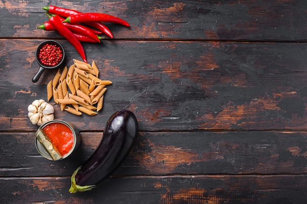 Aubergine penne ingredients eggplant pasta, pepper tomatoe sauce, on old wooden table top view  space for text.