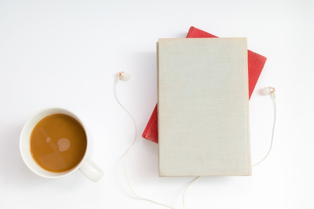 Audio book concept. Headphones, coffee and hard cover book over table.