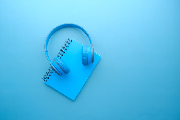 Audio book concept Headphones and notepad on blue background