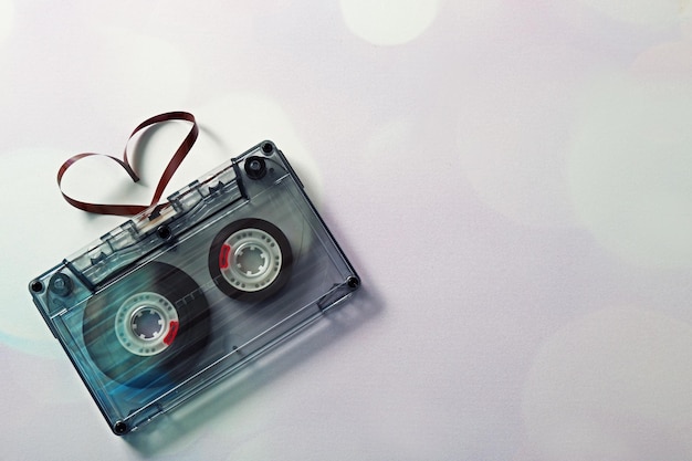 Audio cassette with magnetic tape in shape of hearts on light background