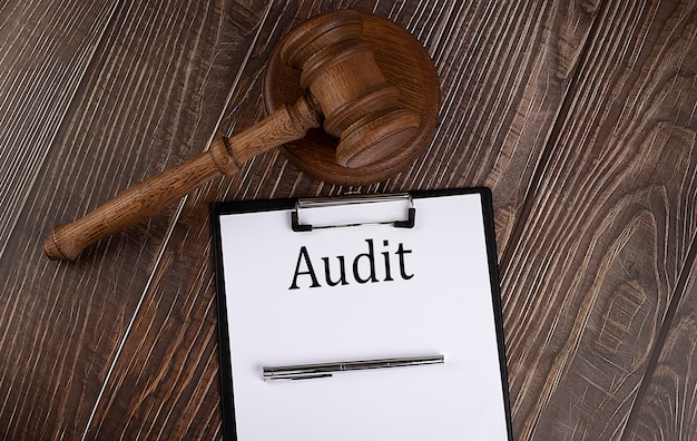 AUDIT text on the paper with gavel on the wooden background