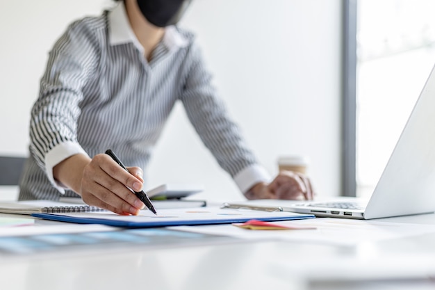 The auditor points to the financial statement, she examines the financial information from the documents prepared by the finance department, before presenting it at the meeting to the management.