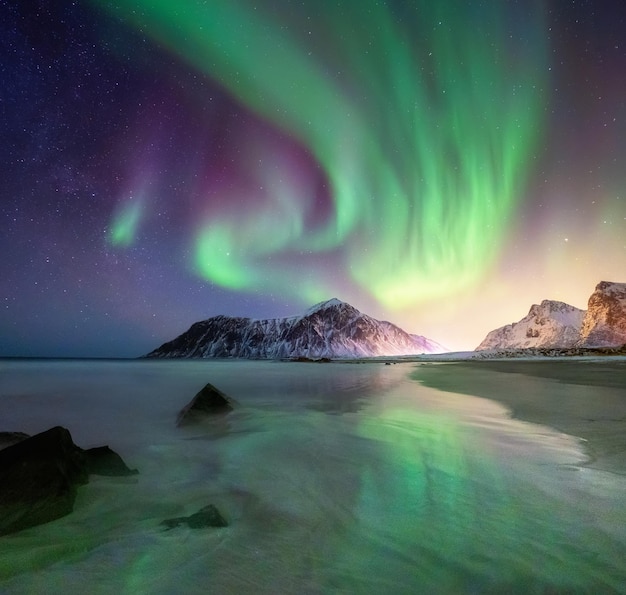 Aurora borealis on the Lofoten islands Norway Green northern lights above mountains and beach Night sky with polar lights Night winter landscape with aurora Natural background in the Norway