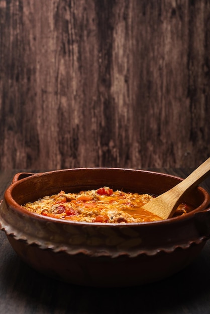 Authentic mexican chicken tinga typical mexican food prepared in a clay pot on a wooden table