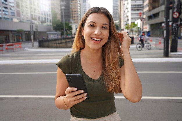 Authentic people outdoors Selfconfident girl with phone looking at camera in empty metropolis in the morning on summer