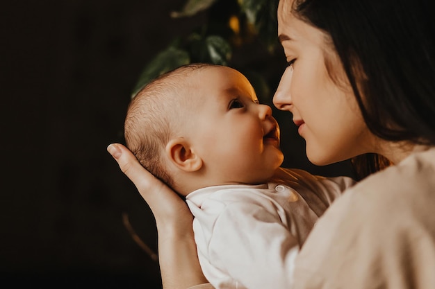 Authentic portrait of mother and newborn daughter in her arms A woman rejoices hugs and kisses a child talks and rejoices her daughter happy smiles on the face of mother and baby