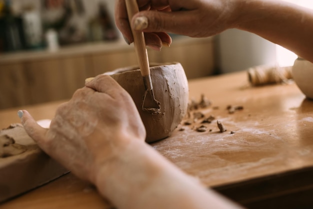 Author's decoration and production of earthenware pottery Handmade ceramic tableware carving with special tools hands in clay