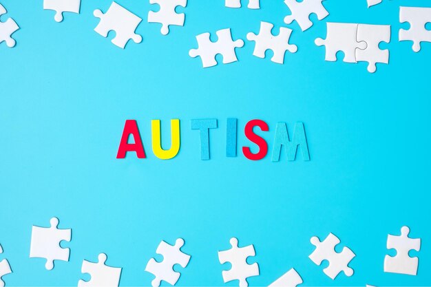 AUTISM text with white puzzle jigsaw pieces on blue background Concepts of health Autistic Spectrum disorder and world Autism awareness day